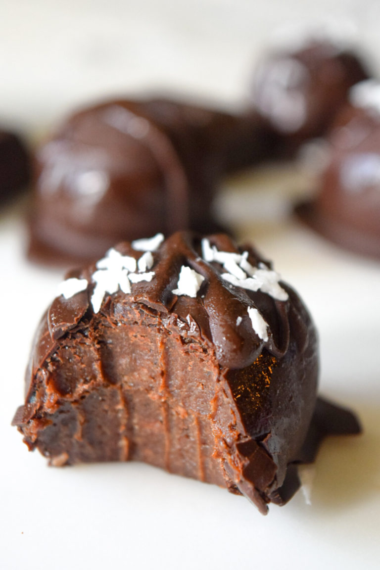 Brownie Truffle with a large bite out of it showcasing the fudge texture in the middle, delicious