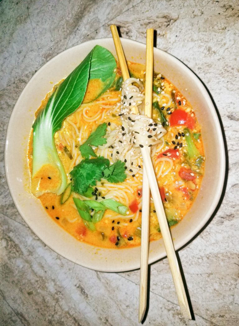 Beautifully twisted ramen noodles with deep orange red curry broth